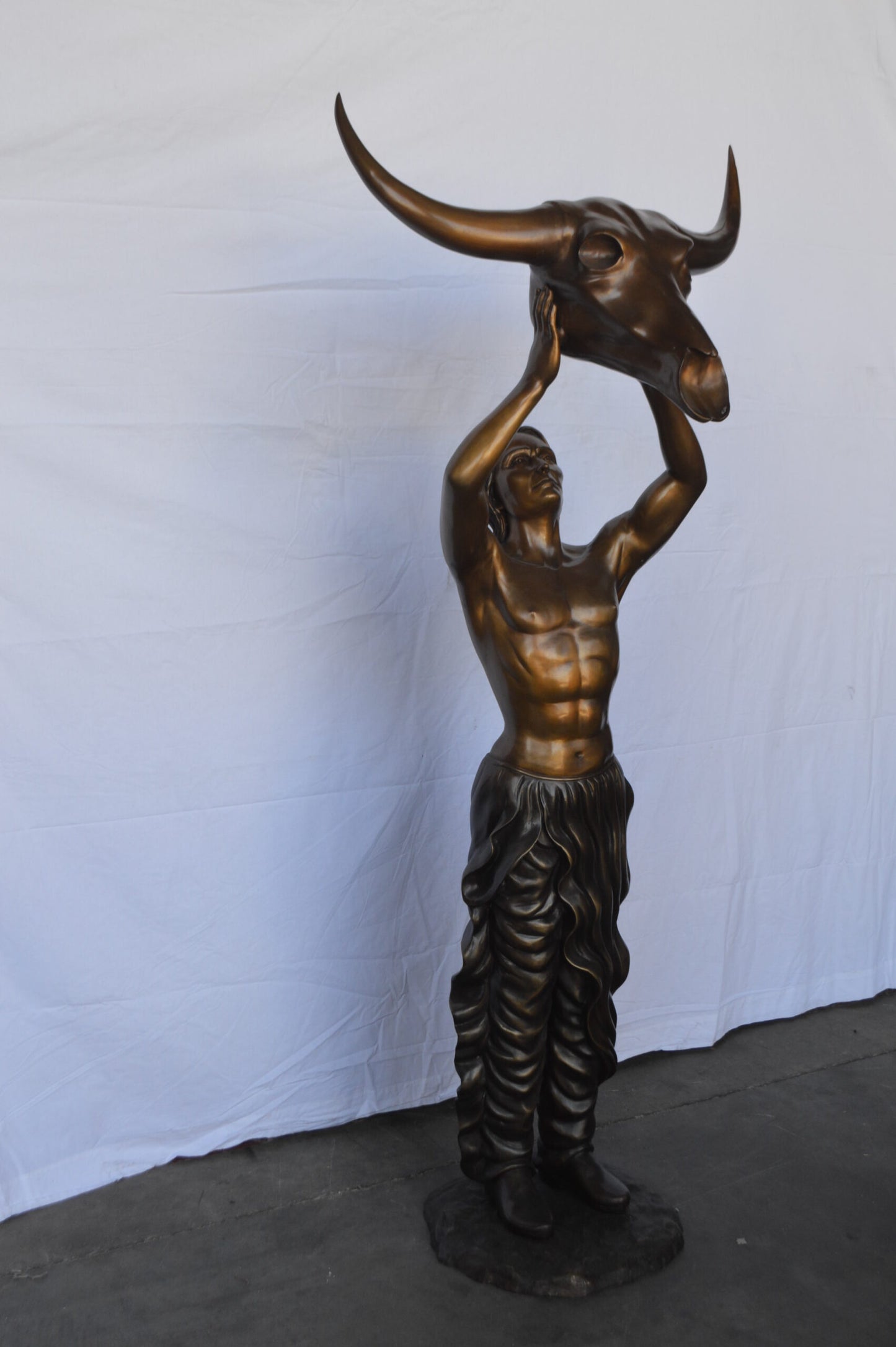 Indian Man Holds a Buffalo Skull Bronze Statue - Size: 29"L x 23"W x 72"H.