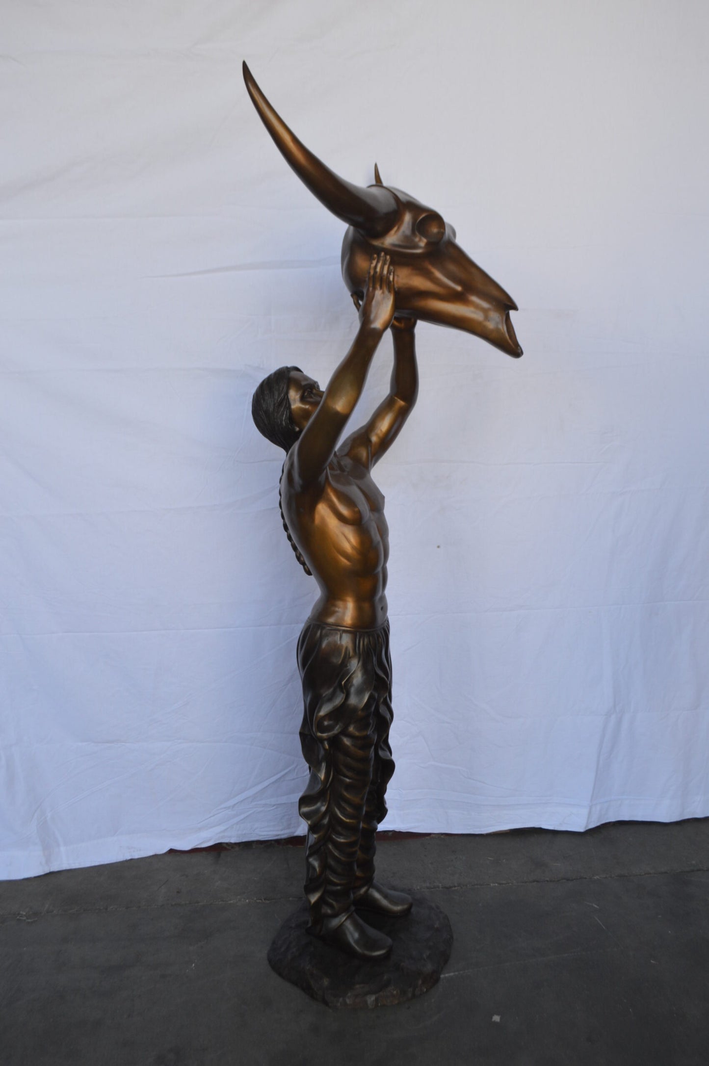 Indian Man Holds a Buffalo Skull Bronze Statue - Size: 29"L x 23"W x 72"H.