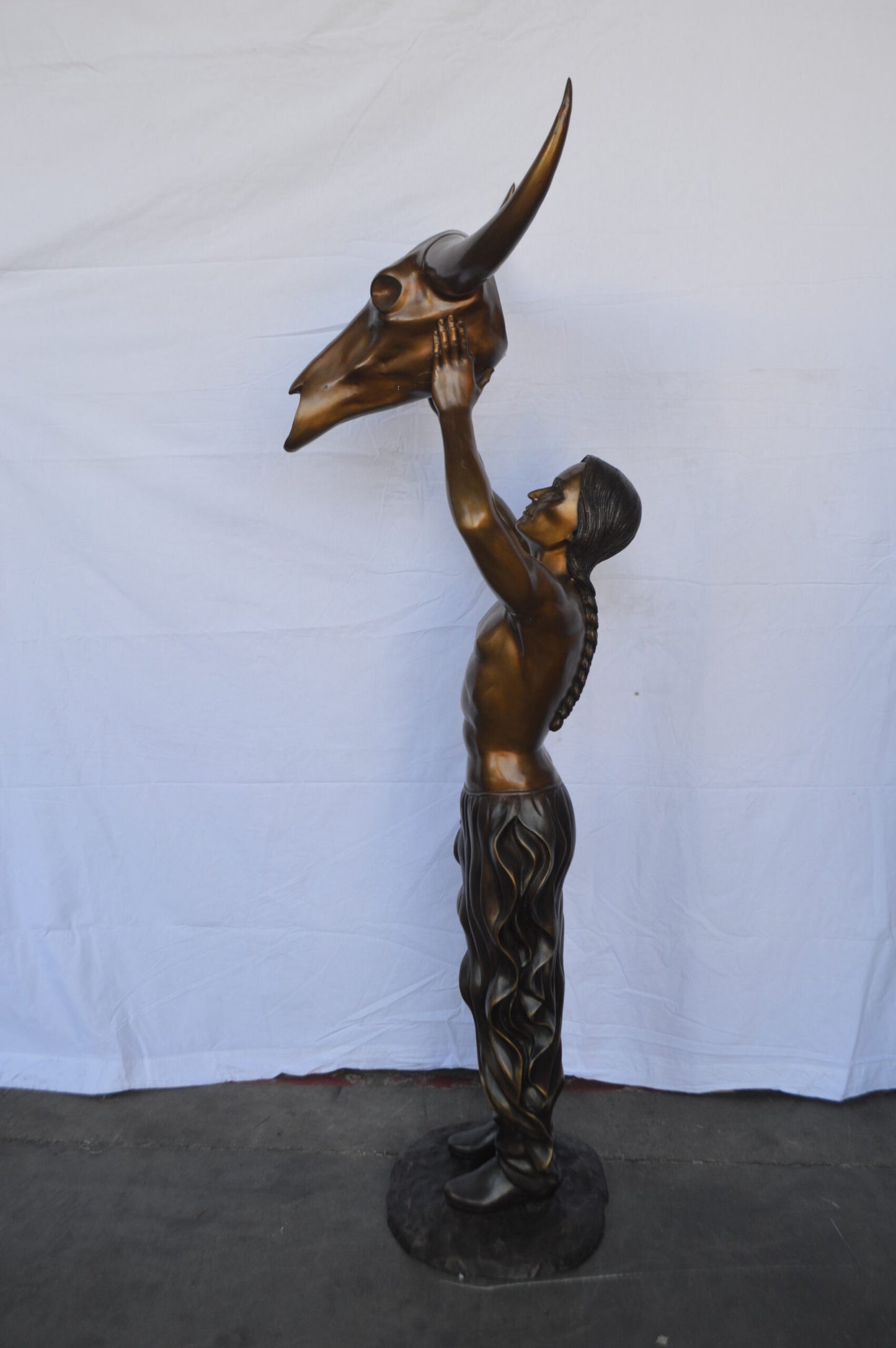 Indian Man Holds a Buffalo Skull Bronze Statue - Size: 29"L x 23"W x 72"H.
