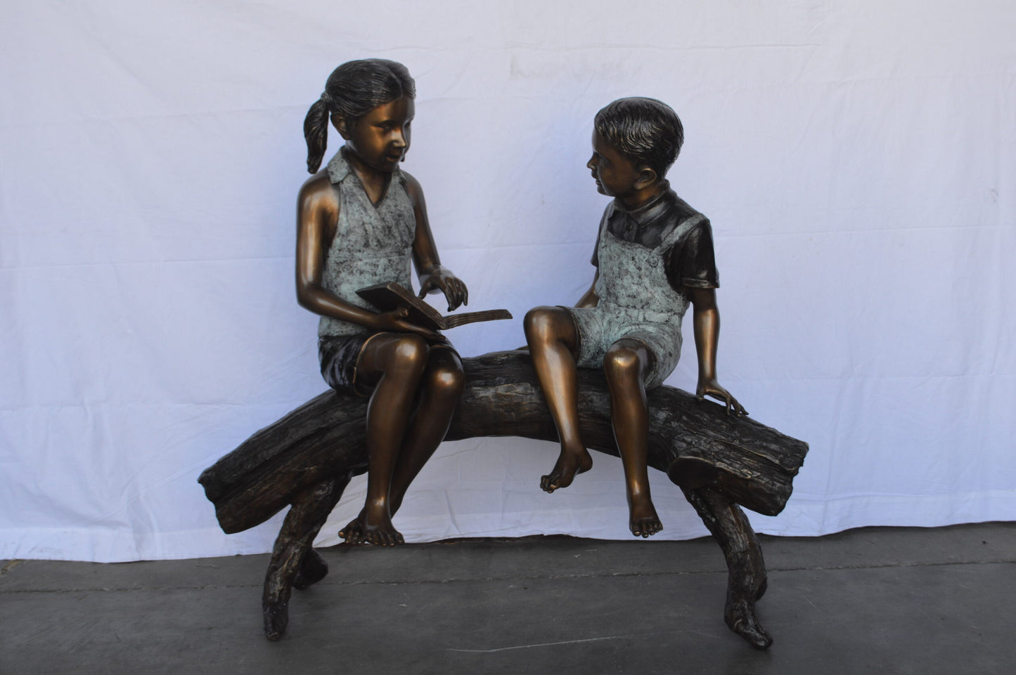 Two Kids on a tree log reading Bronze Statue Large -  Size: 44"L x 17"W x 42"H.