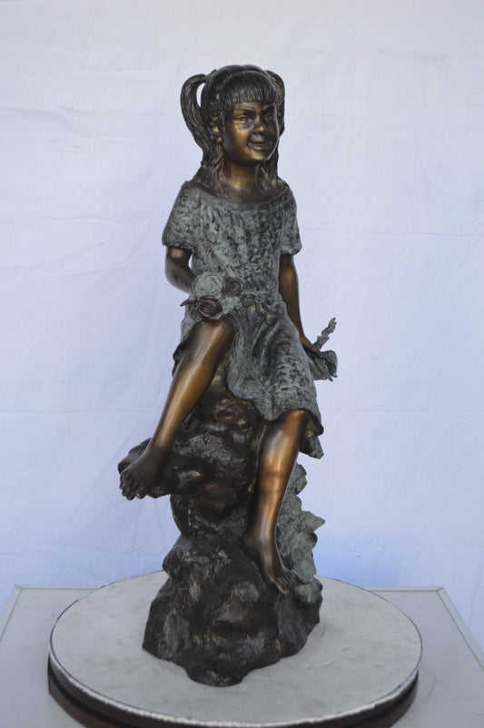 Girl on Tree  Trunk Holding Flowers Bronze Statue -  Size: 26"L x 11"W x 36"H.
