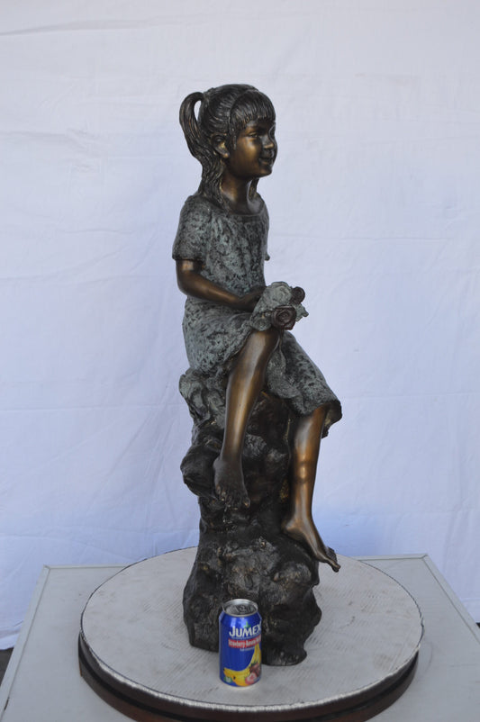 Girl on Tree  Trunk Holding Flowers Bronze Statue -  Size: 26"L x 11"W x 36"H.