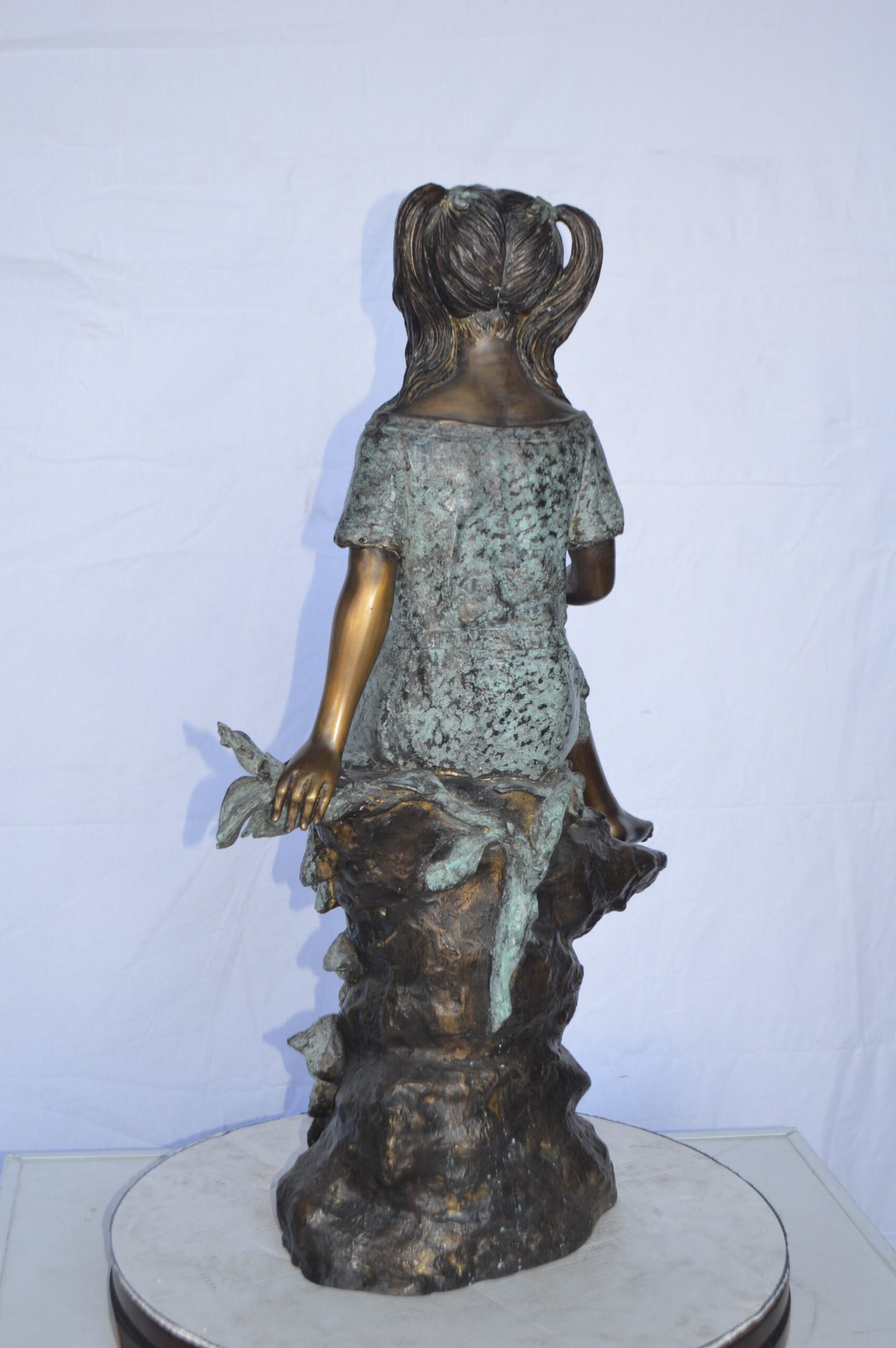 Girl on Tree Trunk Holding Flowers Bronze Statue - Size: 26"L x 11"W x 36"H.