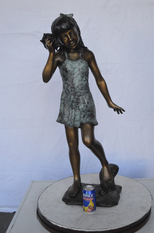 Standing Girl Listening to a Shell Bronze Statue -  Size: 16"L x 12"W x 37"H.