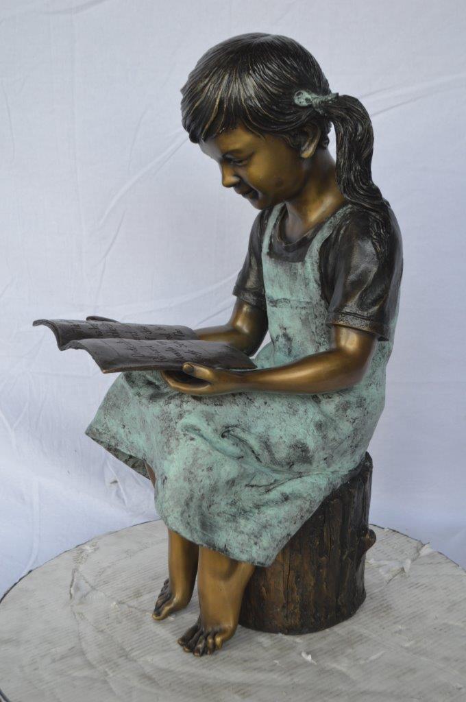 Young girl sitting and reading book bronze statue -  Size: 16"L x 12"W x 27"H.