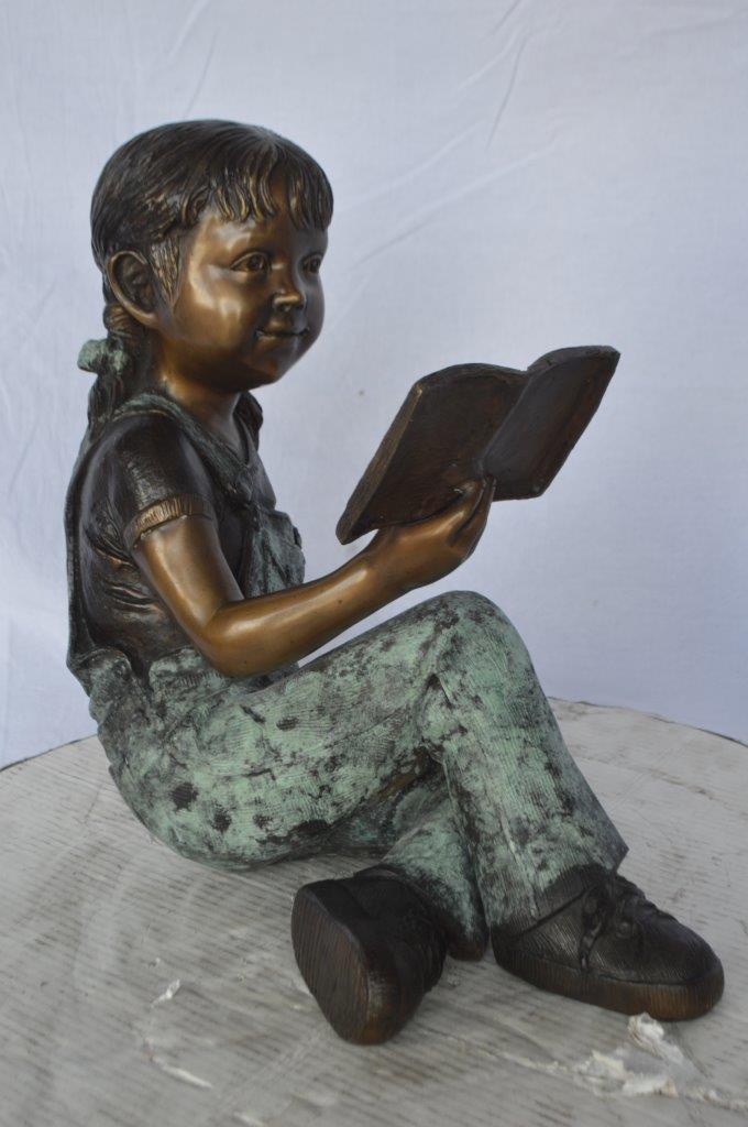 Young girl laying and reading book bronze statue -  Size: 18"L x 9"W x 16"H.