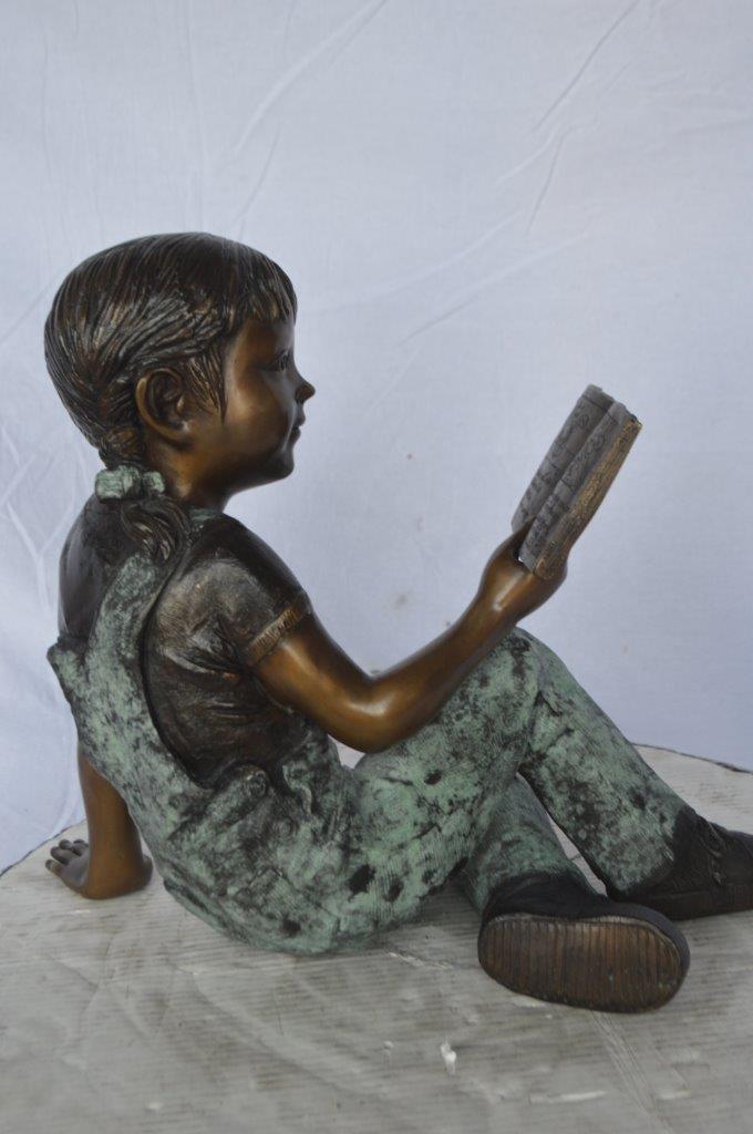 Young girl laying and reading book bronze statue -  Size: 18"L x 9"W x 16"H.