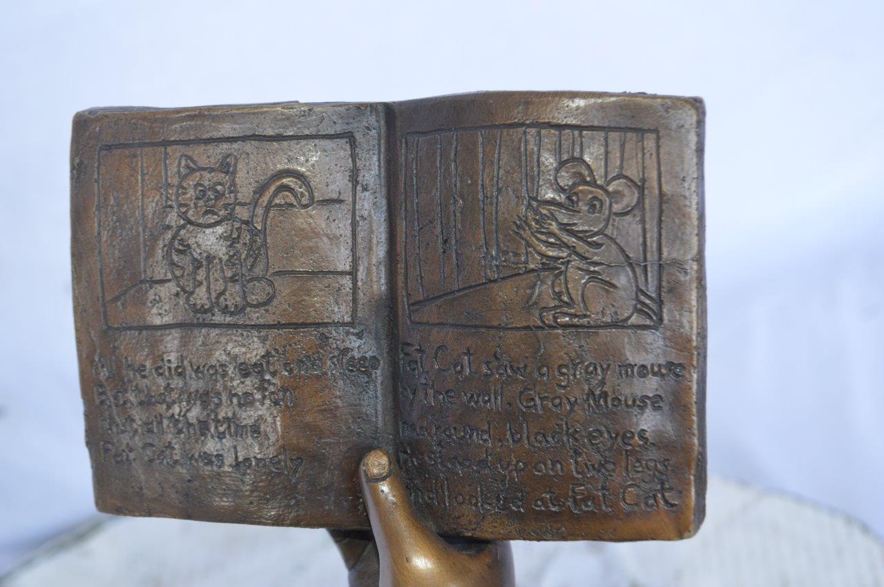 Young girl laying and reading book bronze statue - Size: 18"L x 9"W x 16"H.
