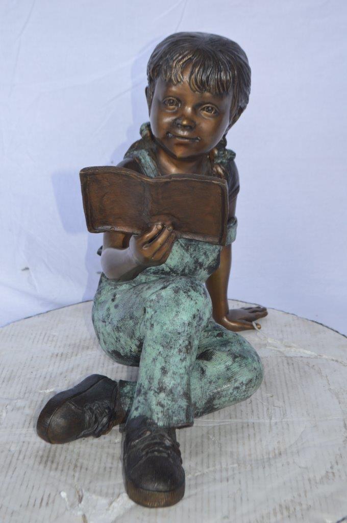 Young girl laying and reading book bronze statue -  Size: 18"L x 9"W x 16"H.
