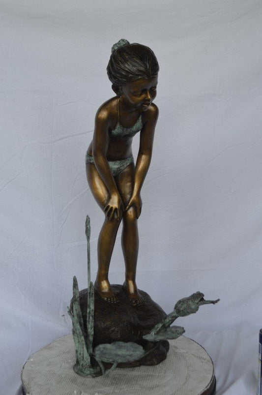 Girl looking at frog jumping bronze fountain - Size: 21"L x 15"W x 38"H.
