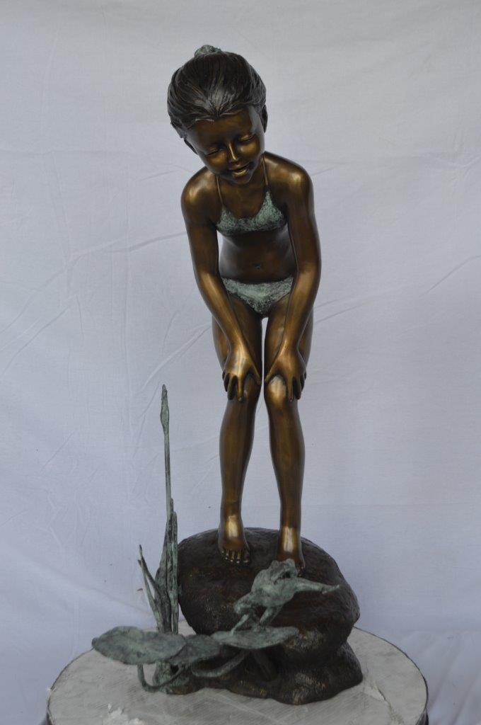 Girl looking at frog jumping bronze fountain - Size: 21"L x 15"W x 38"H.