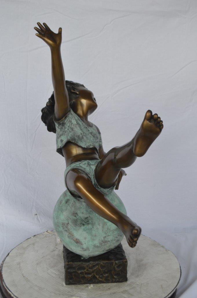 Girl having fun on apple bronze statue - Size: 22"L x 9"W x 31"H.