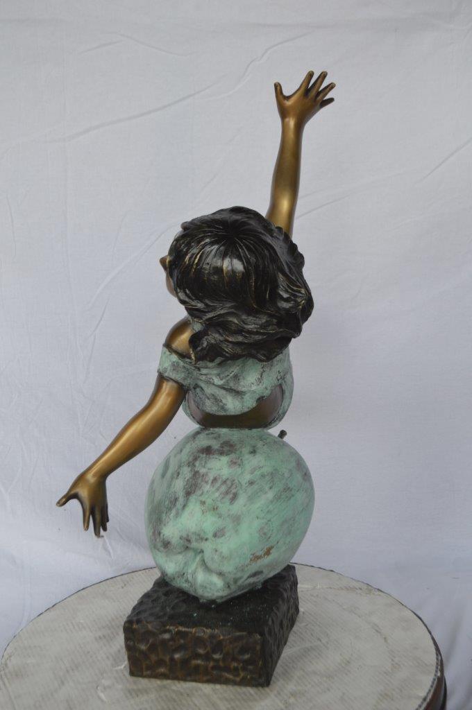 Girl having fun on apple bronze statue - Size: 22"L x 9"W x 31"H.