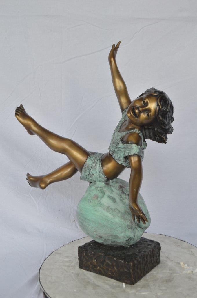 Girl having fun on apple bronze statue - Size: 22"L x 9"W x 31"H.