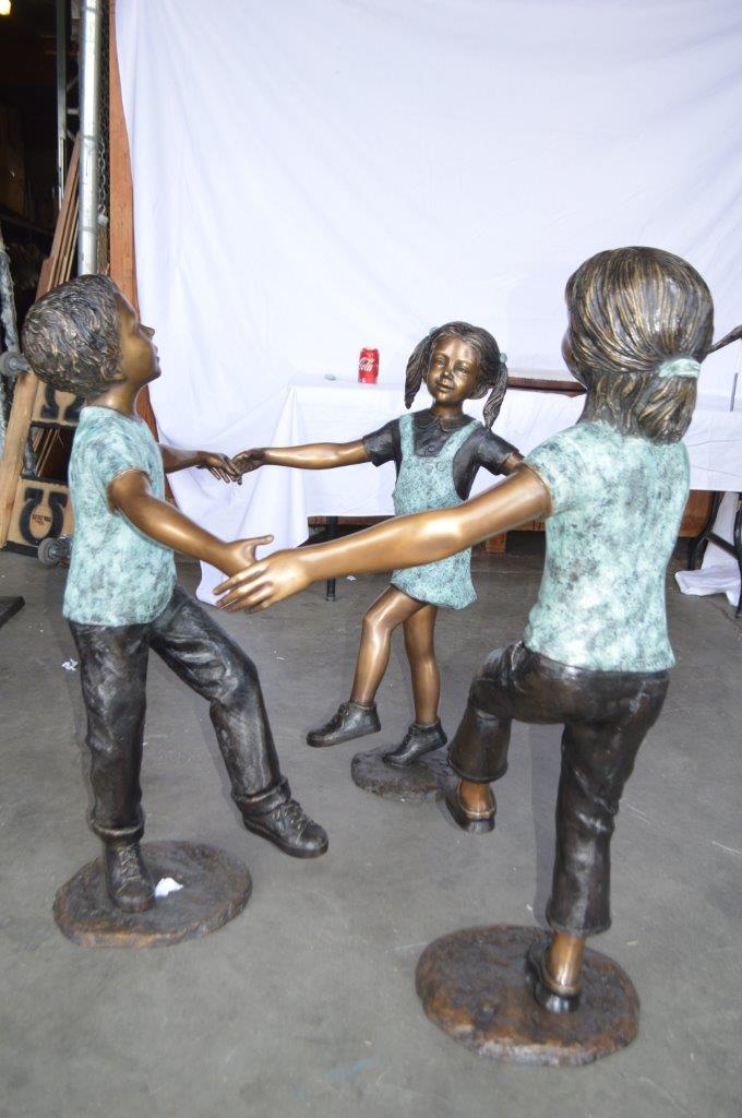 Three children happily holding hands bronze statue - Size: 31"L x 19"W x 41"H.