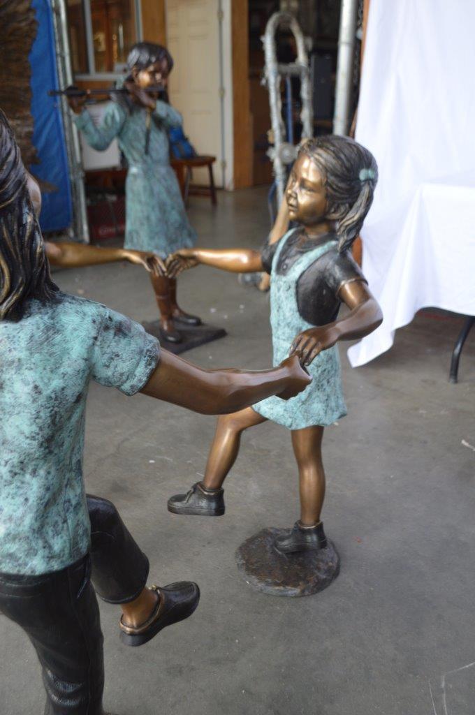 Three children happily holding hands bronze statue - Size: 31"L x 19"W x 41"H.