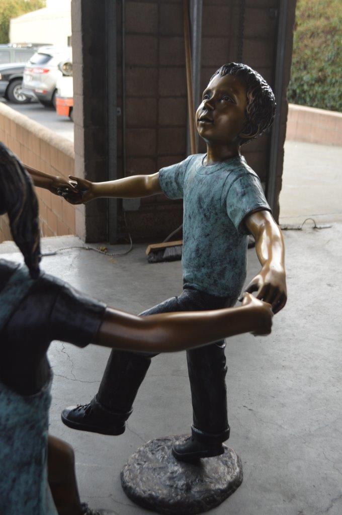 Three children happily holding hands bronze statue - Size: 31"L x 19"W x 41"H.