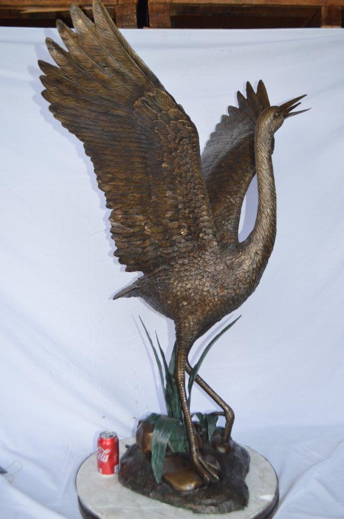Crane standing on a stone bronze statue - Size: 28"L x 32"W x 49"H.