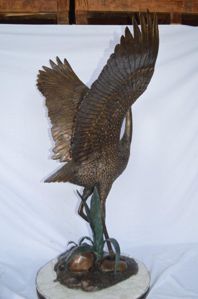 Crane standing on a stone bronze statue - Size: 28"L x 32"W x 49"H.