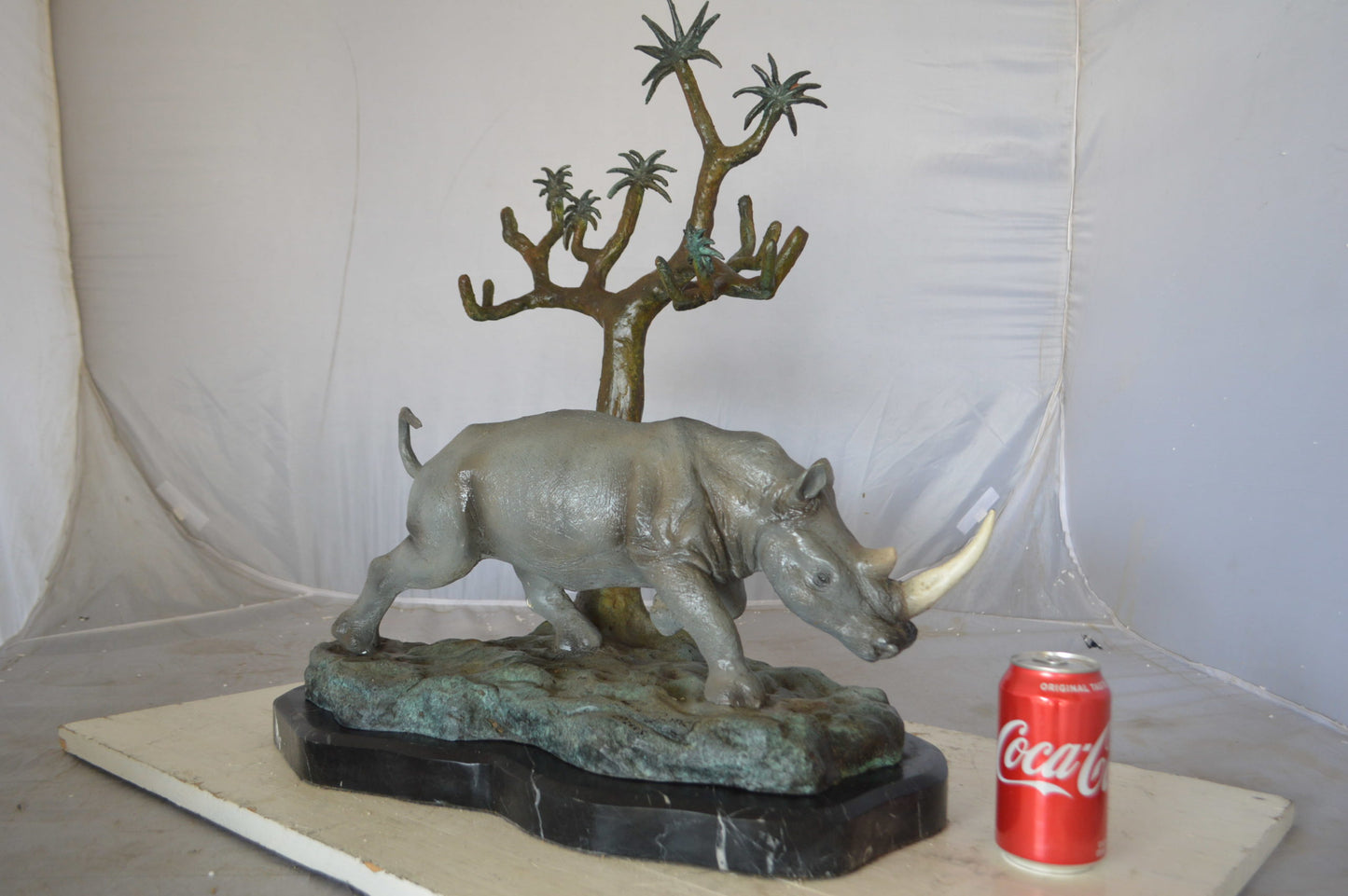Rhino Relaxed under a tree bronze statue - Size: 22"L x 15"W x 25"H.