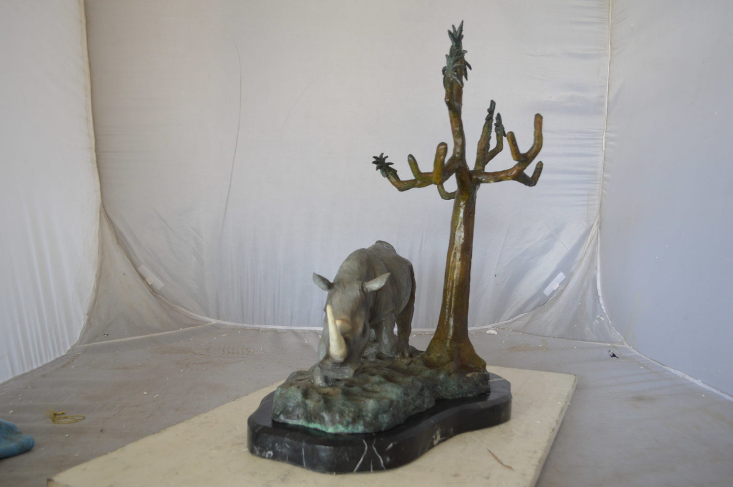 Rhino Relaxed under a tree bronze statue - Size: 22"L x 15"W x 25"H.