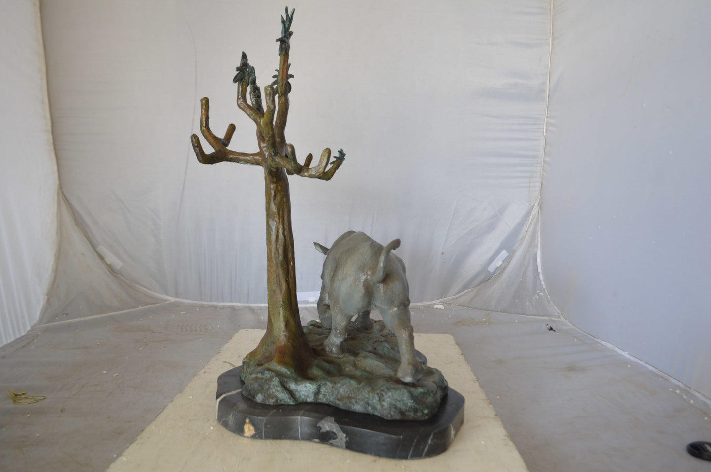 Rhino Relaxed under a tree bronze statue - Size: 22"L x 15"W x 25"H.