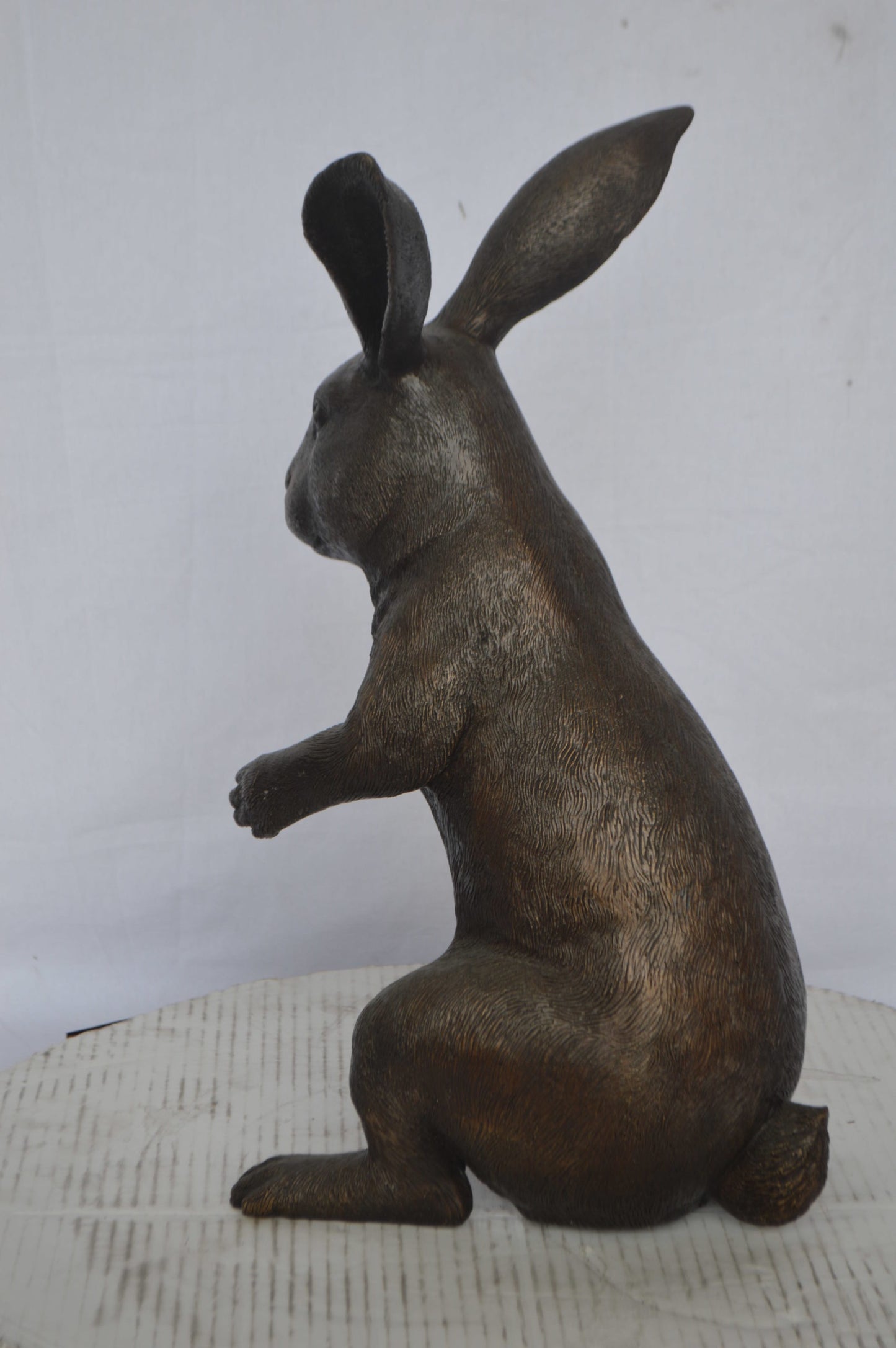 Rabbit looking down bronze statue - Size: 10"L x 12"W x 20"H.