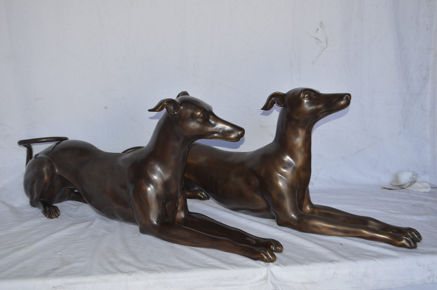 Pair of Greyhound dogs laying down Bronze Statues - Size: 50"L x 11"W x 20"H.