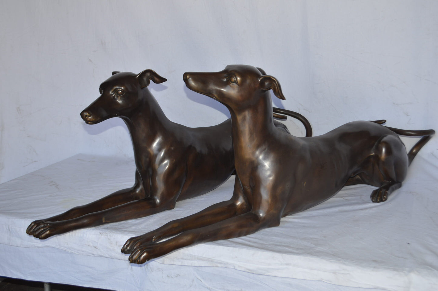Pair of Greyhound dogs laying down Bronze Statues - Size: 50"L x 11"W x 20"H.