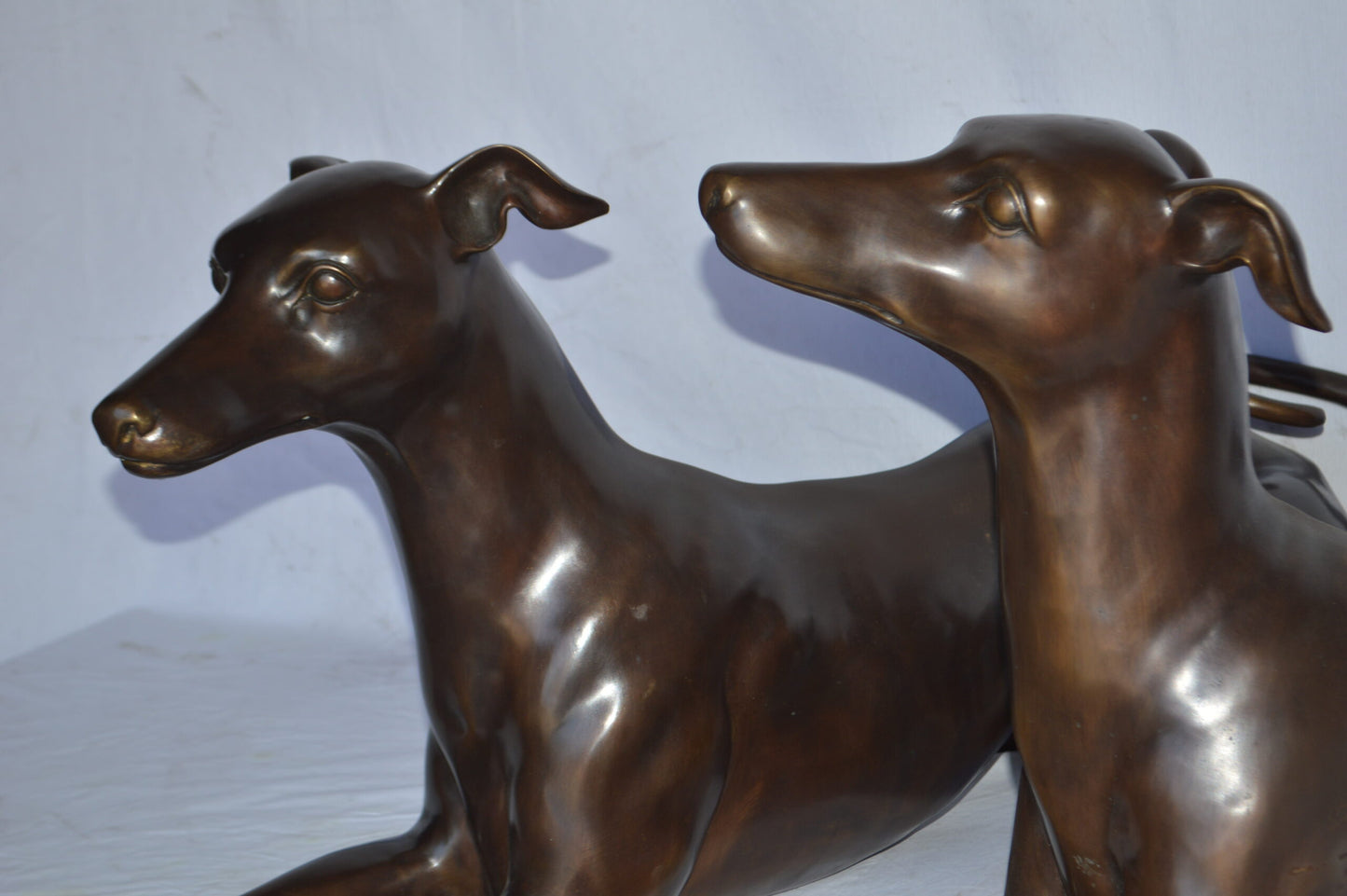 Pair of Greyhound dogs laying down Bronze Statues - Size: 50"L x 11"W x 20"H.