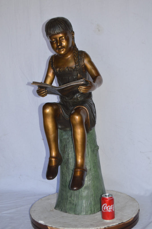 Girl Sitting on a Tree Stump, Reading Bronze Statue - Size: 15"L x 20"W x 22"H.