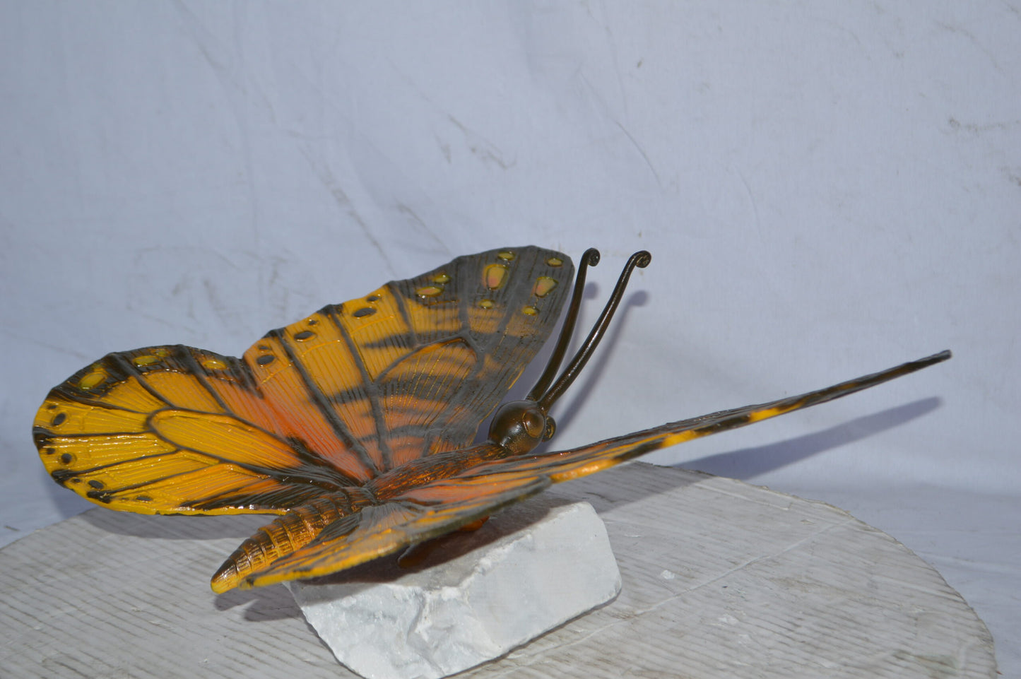Orange Monarch butterfly bronze statue on a  rock - Size: 14"L x 16"W x 8"H.