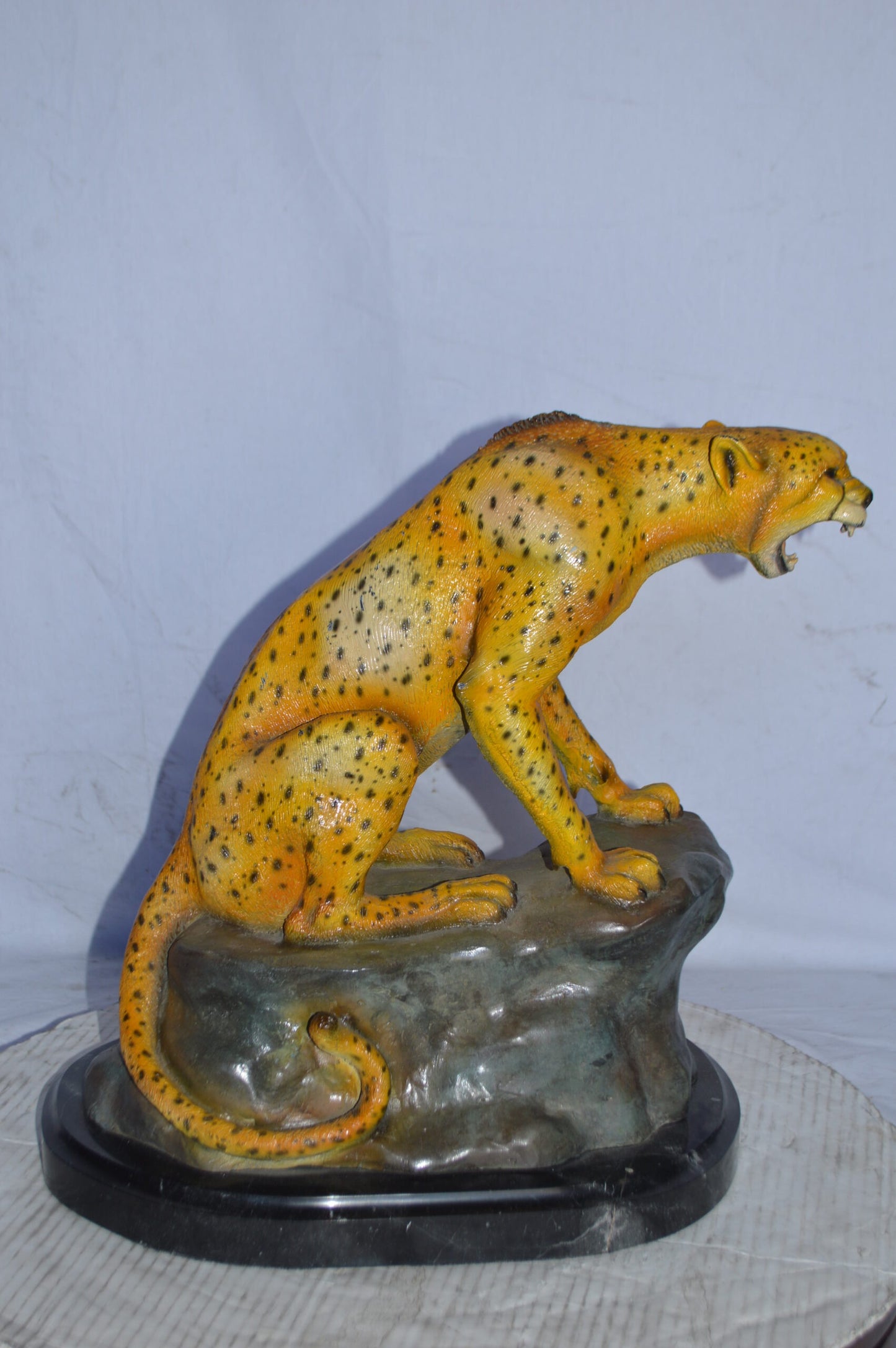 Cheetah sitting on a rock growling bronze statue - Size: 18"L x 12"W x 18"H.