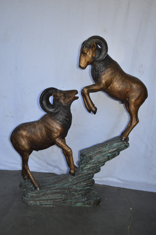 Two Life Size Rams on a rock Bronze Statue - Size: 49"L x 20"W x 64"H.