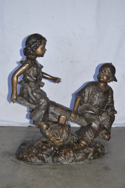 A Boy and a Girl Playing Seesaw Bronze Statue - Size: 17"L x 33"W x 36"H.