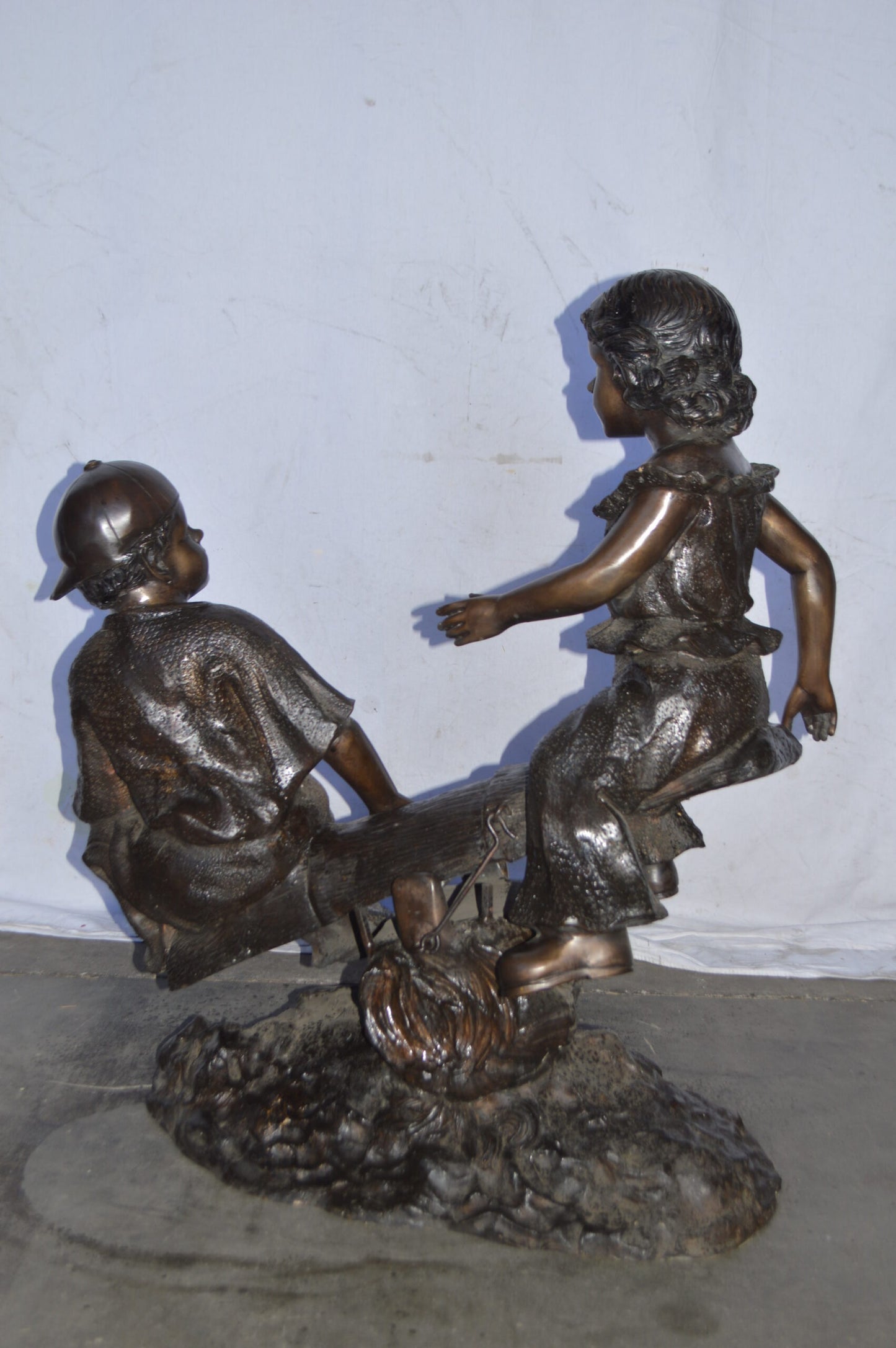 A Boy and a Girl Playing Seesaw Bronze Statue - Size: 17"L x 33"W x 36"H.