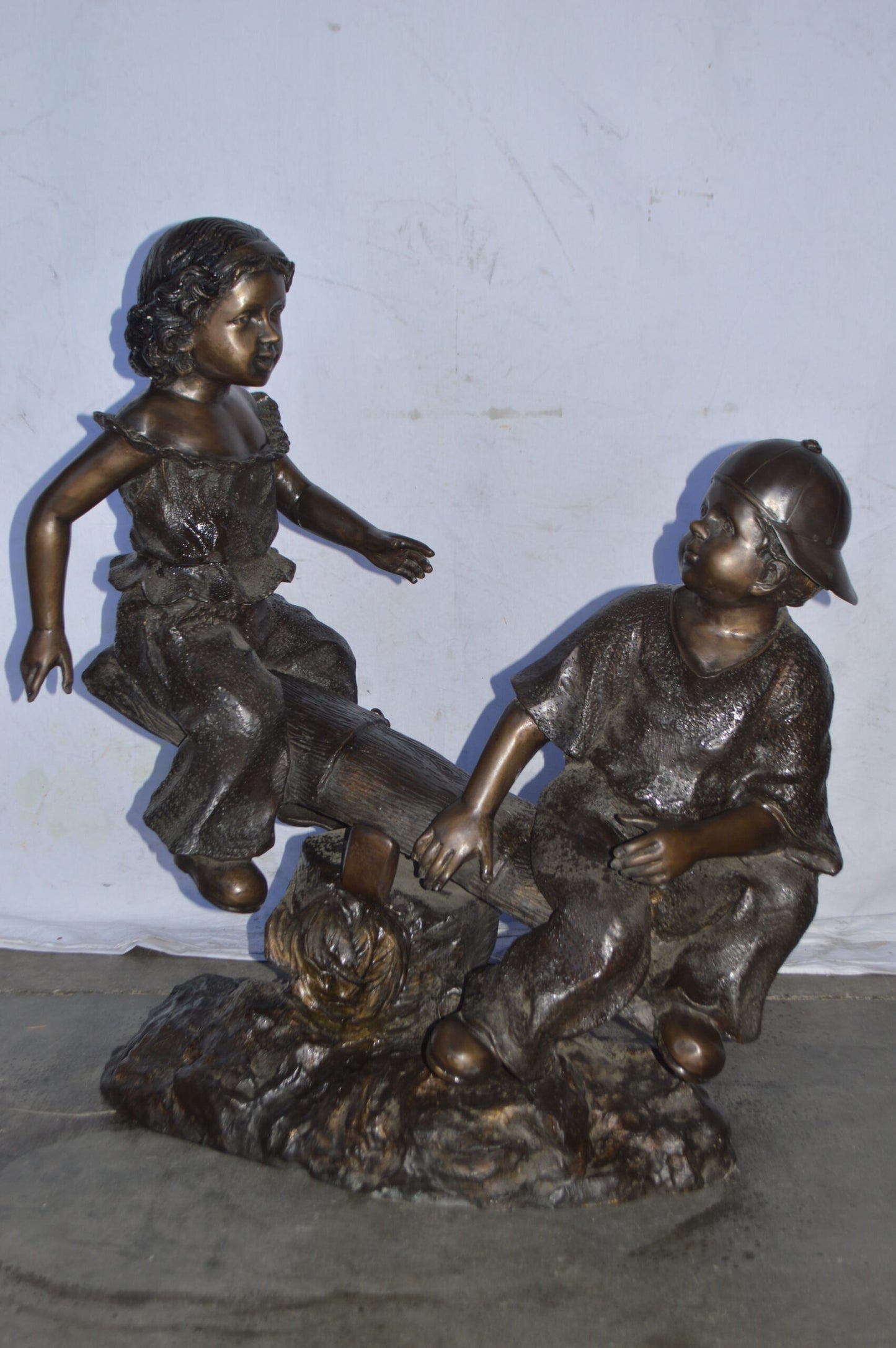 A Boy and a Girl Playing Seesaw Bronze Statue - Size: 17"L x 33"W x 36"H.