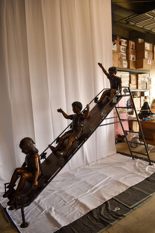 Lifsize Three kids playing on a slide bronze sculpture 114" x 18" x 83"H