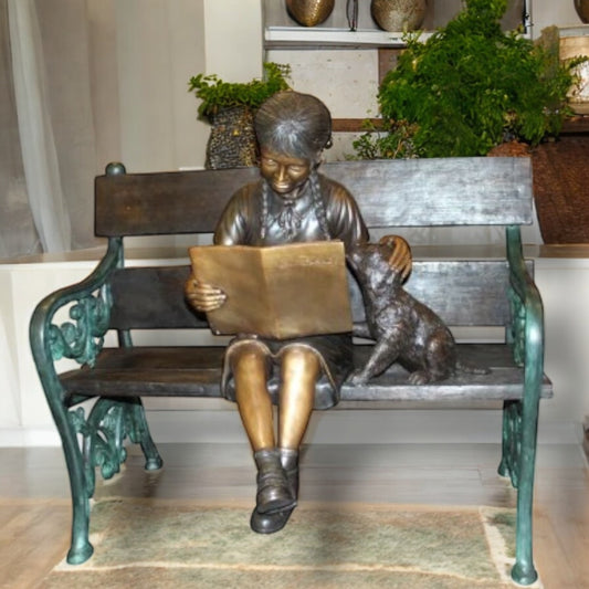 Girl sitting with her dog on a bench, reading Bronze Statue - 27" x 39" x 32"H