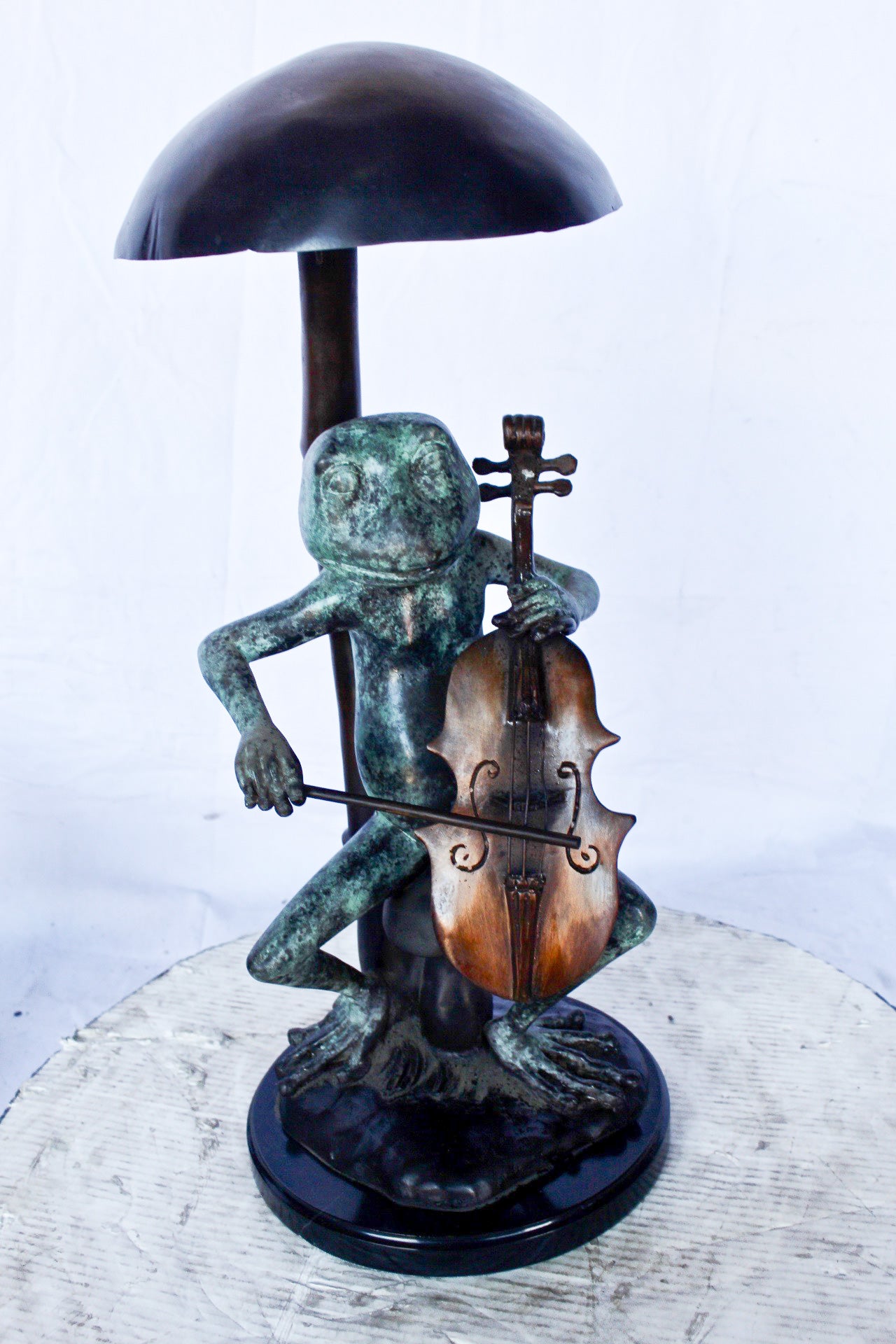 Frog playing cello under mushroom bronze statue - Size: 10"L x 10"W x 24"H.