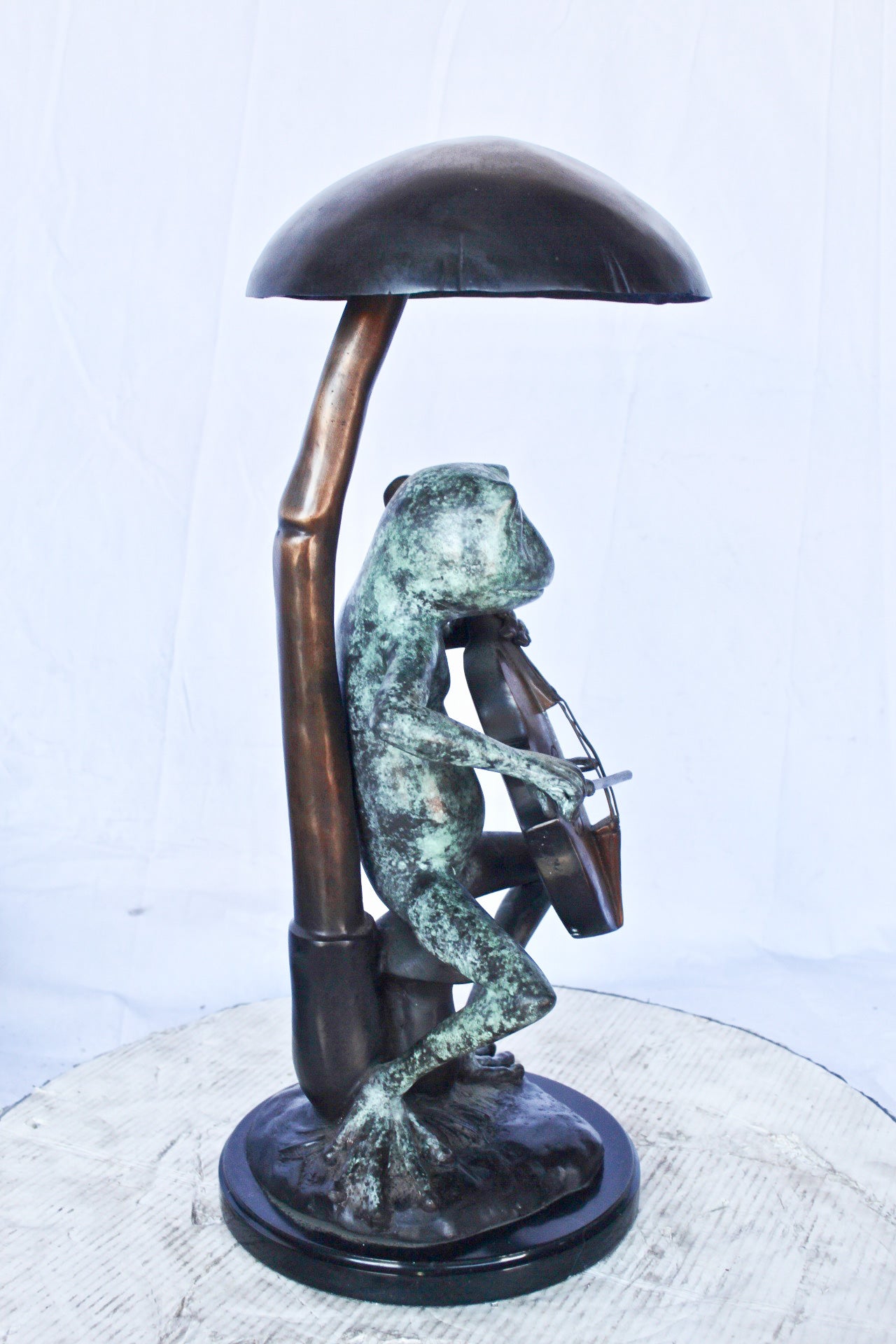 Frog playing cello under mushroom bronze statue - Size: 10"L x 10"W x 24"H.