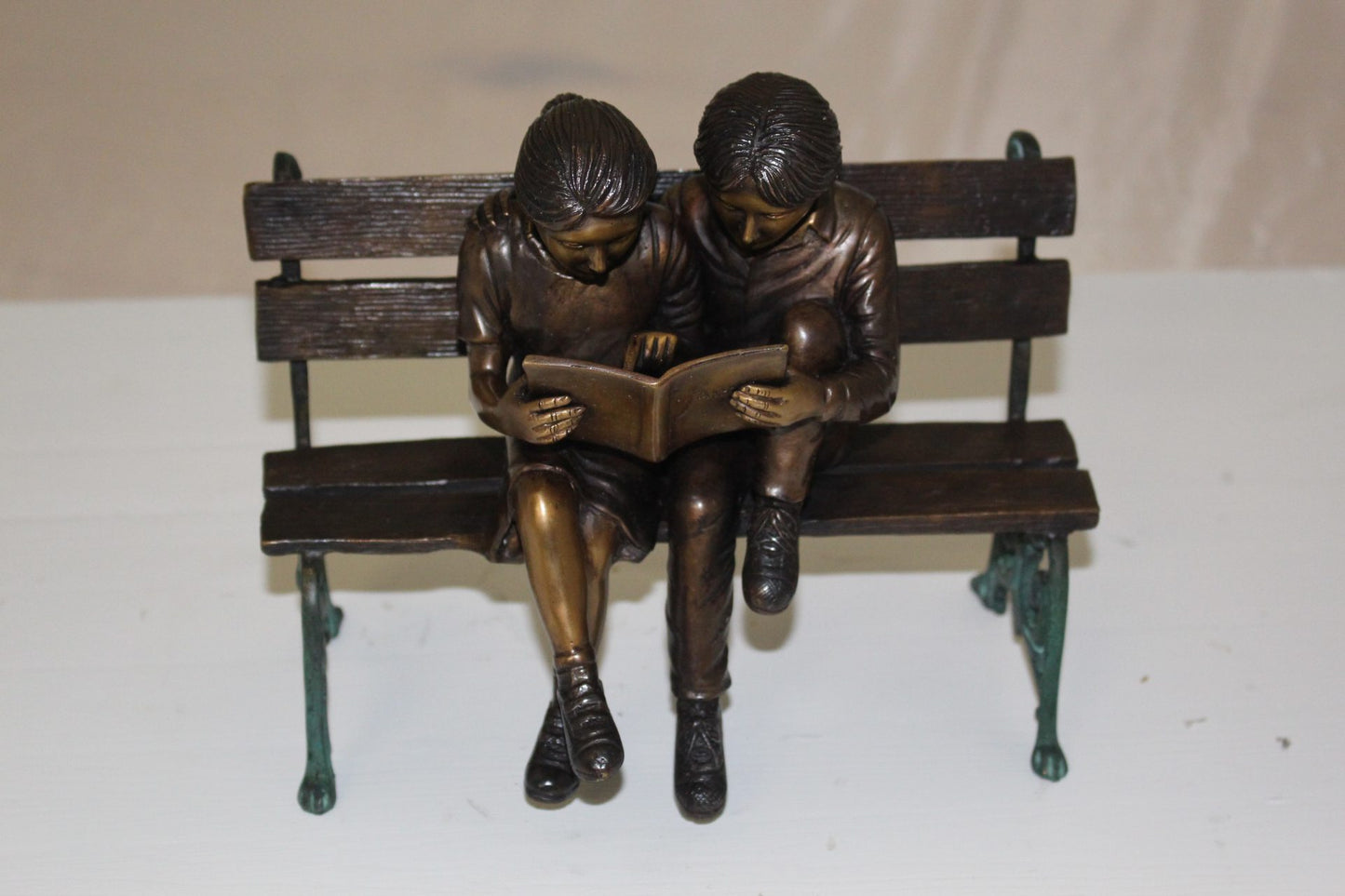 Two kids on bench reading a book - Bronze Statue - Size: 9"L x 6"W x 8"H.