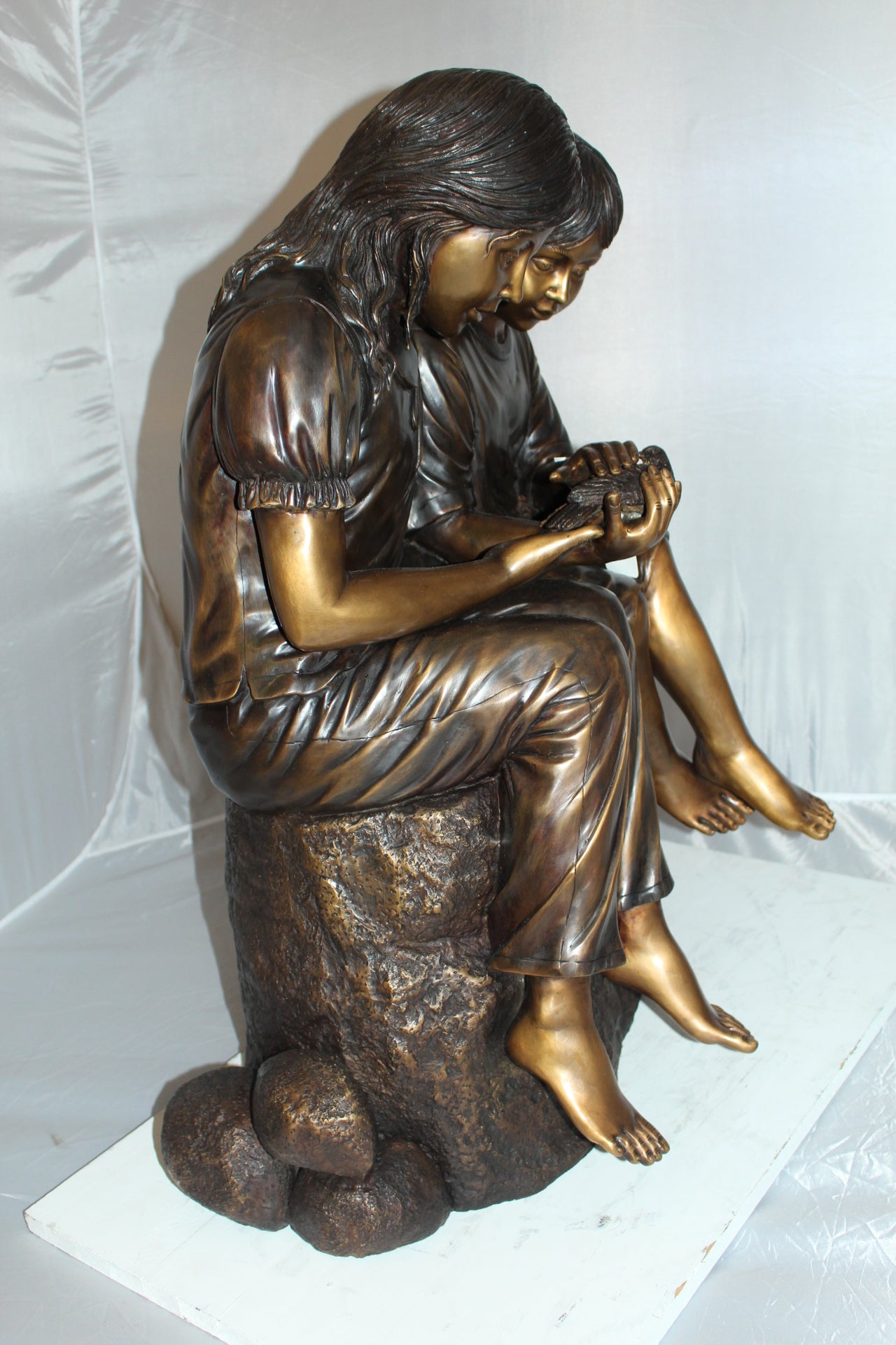 Two kids holding a bird Bronze Statue - Size: 18"L x 26"W x 34"H.