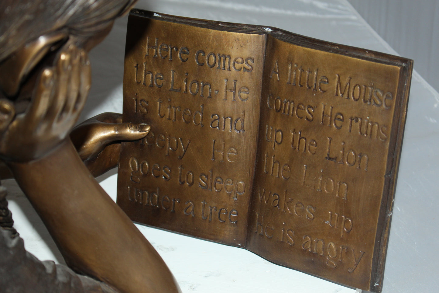 Girl laying reading a book Bronze Statue - Size: 36"L x 17"W x 18"H.