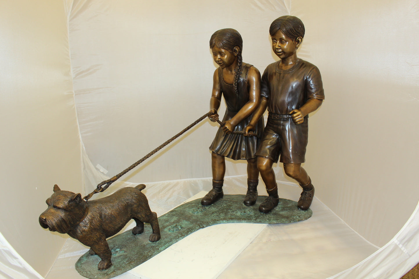 Two Kids Walking a dog Bronze Statue - Size: 55"L x 28"W x 37"H.