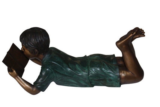 boy laying reading book bronze Statue - Size: 24"L x 10"W x 11"H.