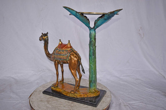 Camel Standing Under A Palm Tree Bronze Statue - Size: 20"L x 29"W x 25"H.