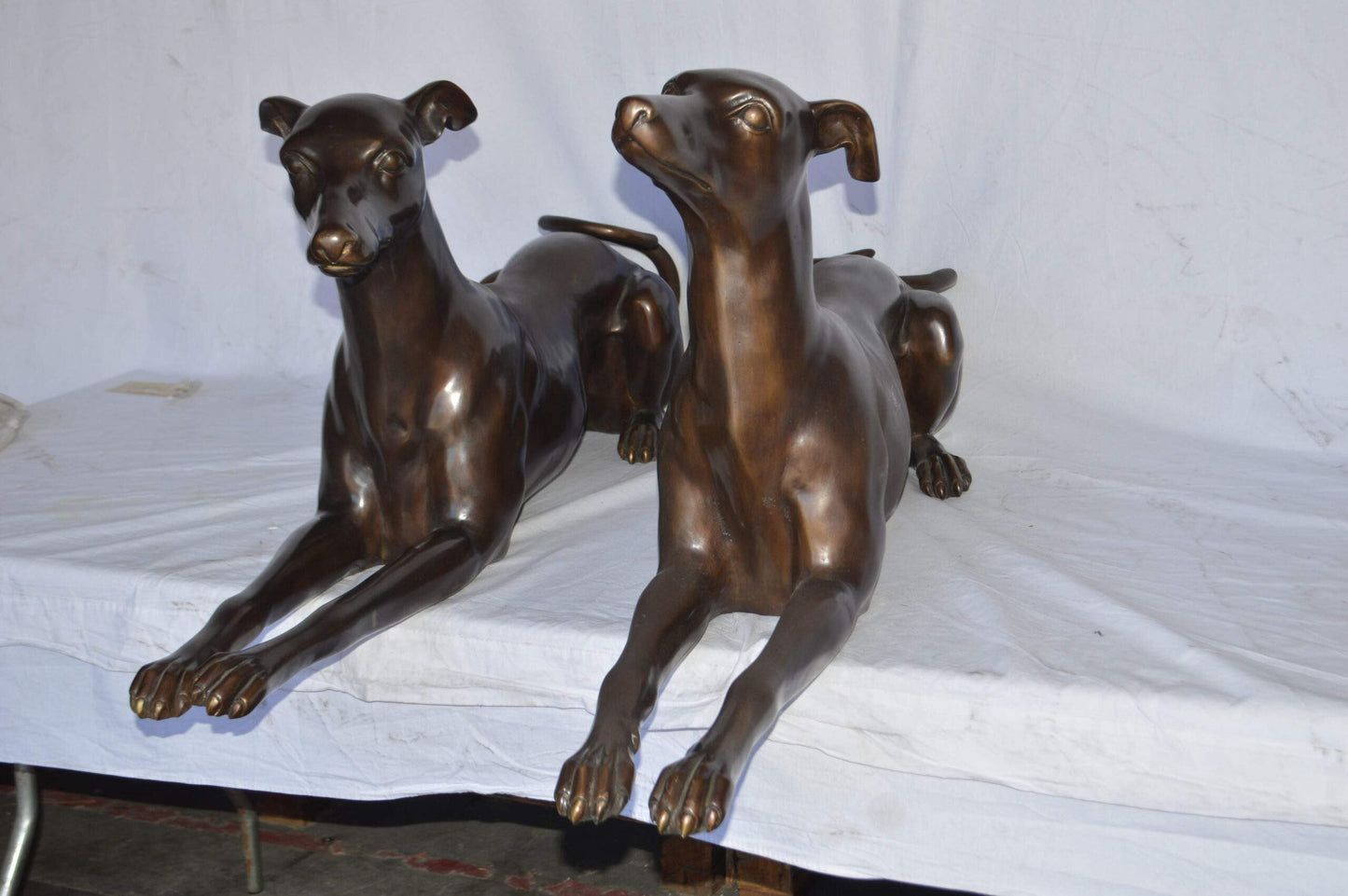 Pair of Greyhound dogs laying down Bronze Statues - Size: 50"L x 11"W x 20"H.