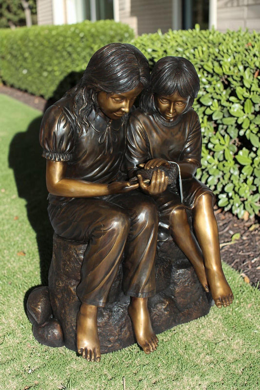 Two kids holding a bird Bronze Statue - Size: 18"L x 26"W x 34"H.