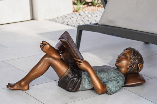Kid on A Pillow Reading a Book Bronze Statue - Size: 32"L x 13"W x 12"H.